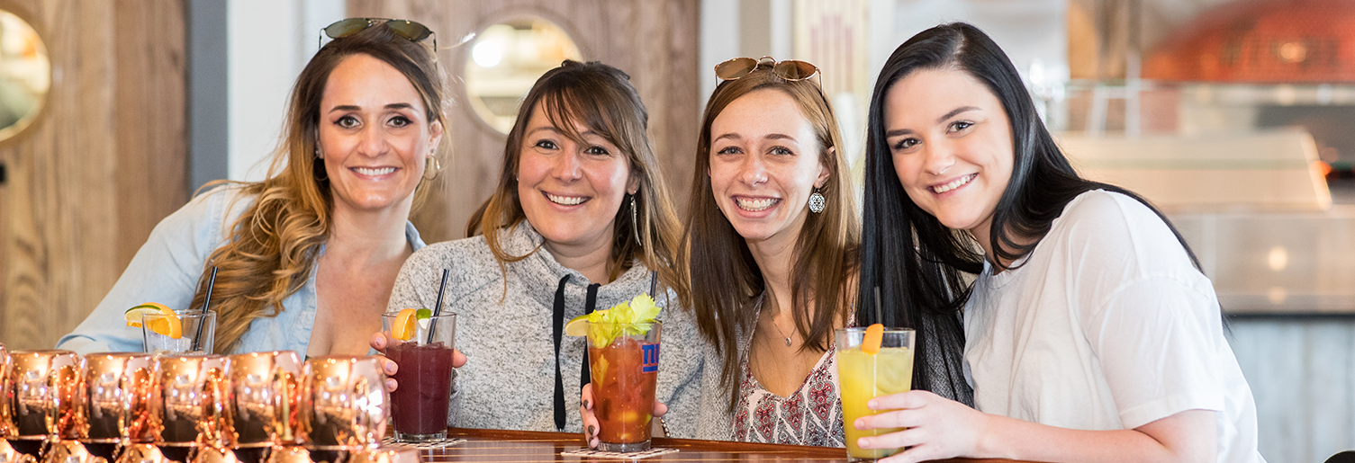 four young woman at The Windlass' bar posing for a picture with cocktail drinks in hand